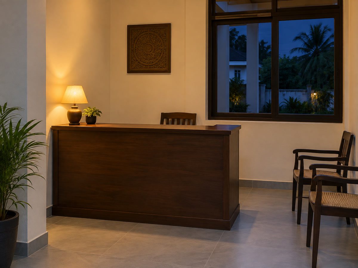 Front desk counter at dusk, a small lamp, empty chairs, no signage
